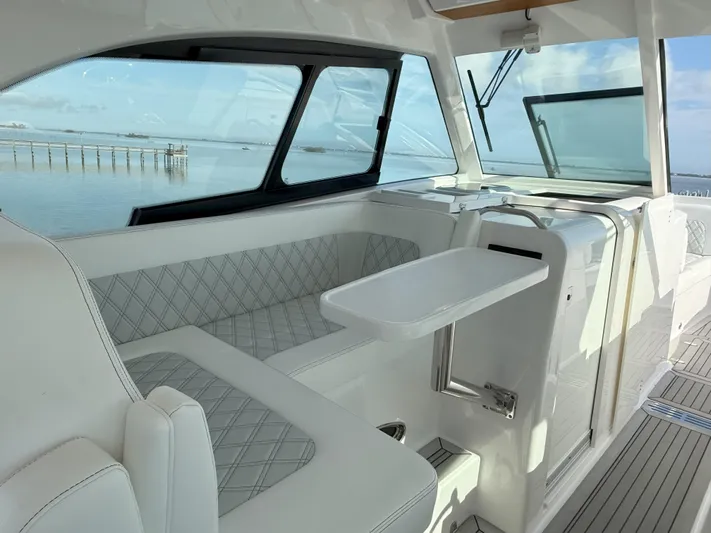  Yacht Photos Pics 2022 Southport 33 DC boat interior with elegant seating and table, overlooking serene water.