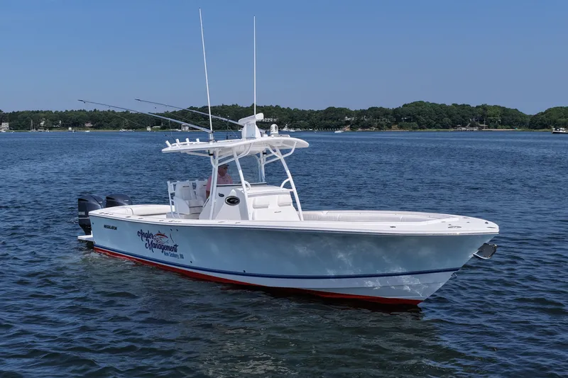 Angler Management Yacht Photos Pics 2013 Regulator 34 Center Console boat on calm water, with scenic shoreline background.