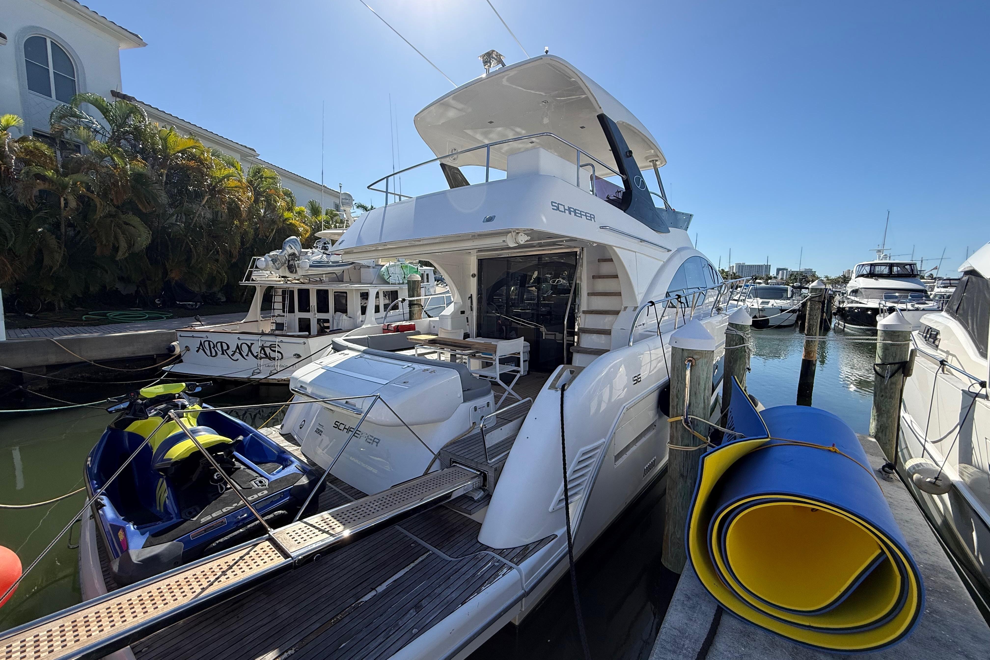 2017 Schaefer 56 yacht docked at marina with jet ski and rolled mat nearby.