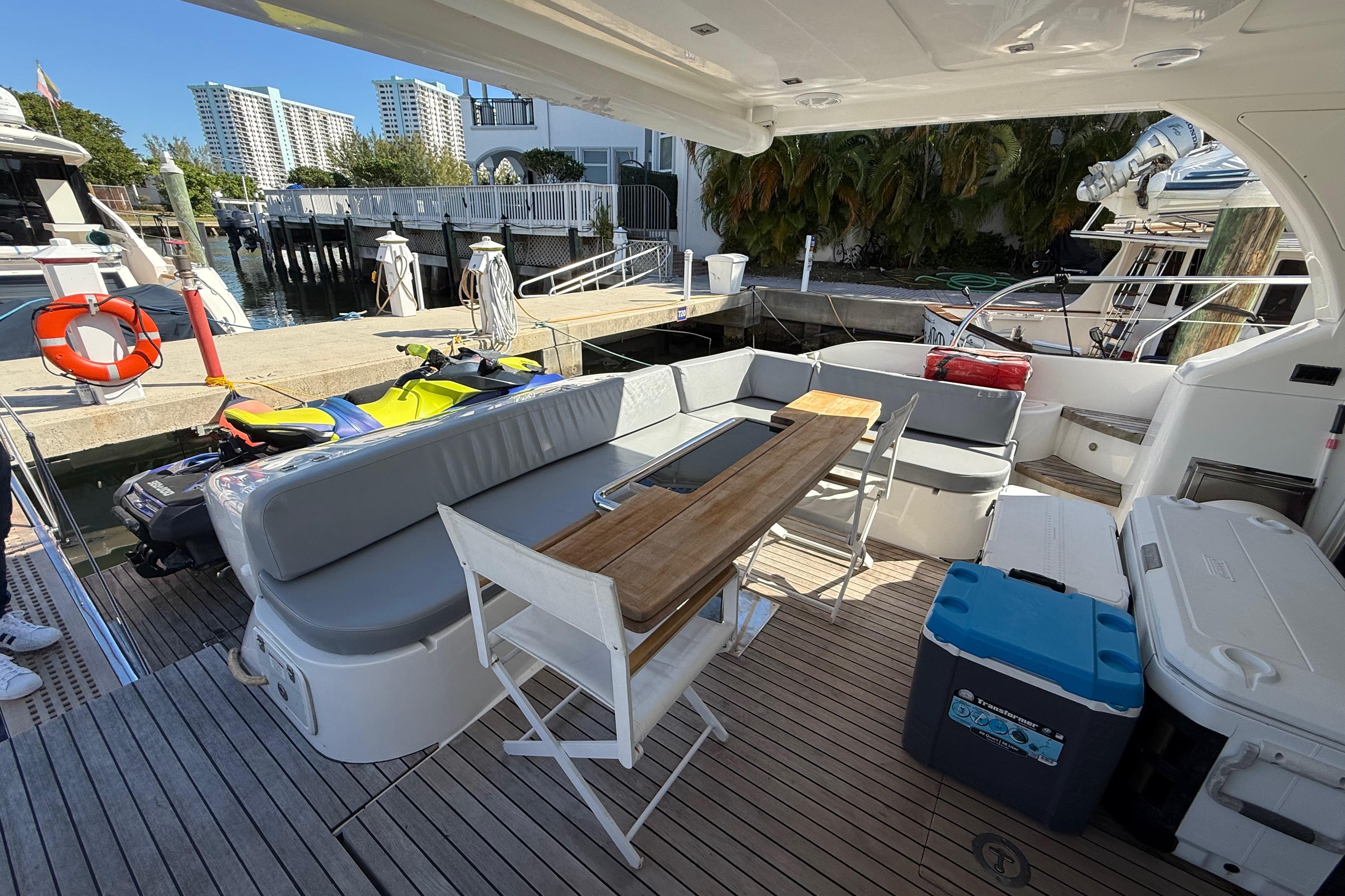 Luxurious 2017 Schaefer 56 yacht deck with seating, table, and coolers at a marina.