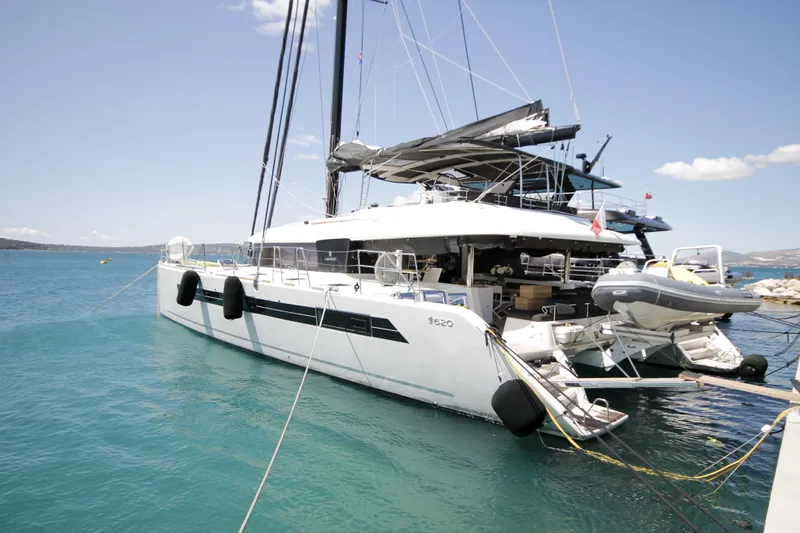  Yacht Photos Pics 2019 Lagoon 620 Essense catamaran docked in clear blue water.