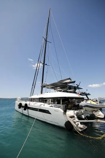  Yacht Photos Pics 2019 Lagoon 620 Essense catamaran docked in clear blue water.