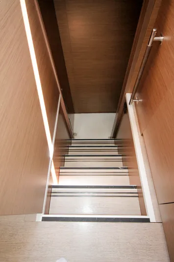  Yacht Photos Pics Staircase inside 2019 Lagoon 620 Essense yacht, featuring sleek wooden design.