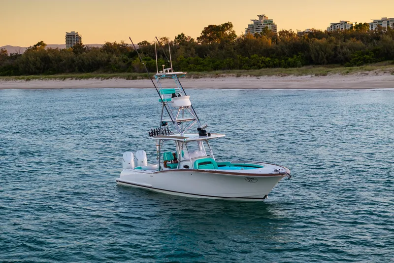 Toto II Yacht Photos Pics 2019 Mag Bay 33 CC boat on calm water near a sandy shoreline at sunset.