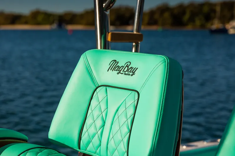 Toto II Yacht Photos Pics Teal seat on 2019 Mag Bay 33 CC boat, with logo, against a serene water backdrop.
