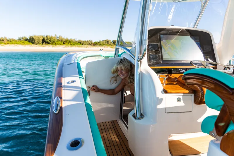 Toto II Yacht Photos Pics 2019 Mag Bay 33 CC boat on water, featuring a smiling person near the helm.
