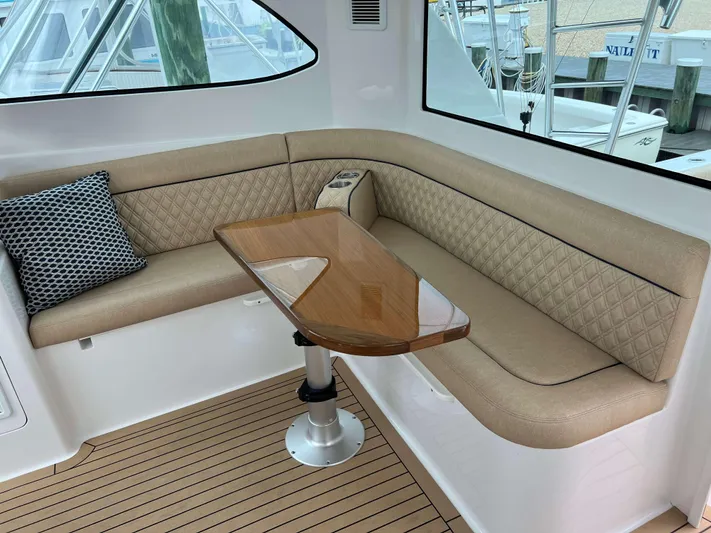  Yacht Photos Pics 2021 Henriques 42 Express Hardtop Bridge interior with beige seating and wooden table.