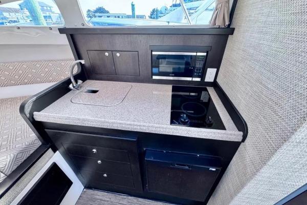 Modern kitchenette in 2022 Stamas 370 Aegean boat with sink, stove, and microwave.