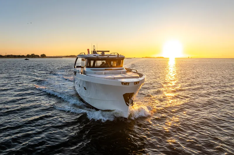 The Calm Down Yacht Photos Pics 2024 Bluegame BGX63 yacht cruising at sunset on open water.