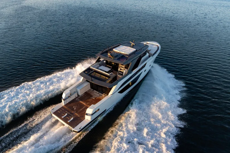 The Calm Down Yacht Photos Pics 2024 Bluegame BGX63 yacht cruising on open water, aerial view.