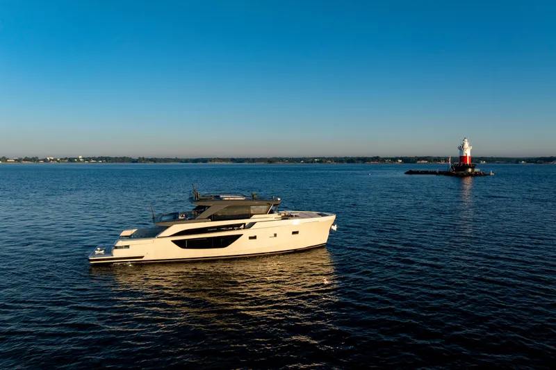 The Calm Down Yacht Photos Pics 2024 Bluegame BGX63 yacht cruising near a lighthouse on a calm sea.