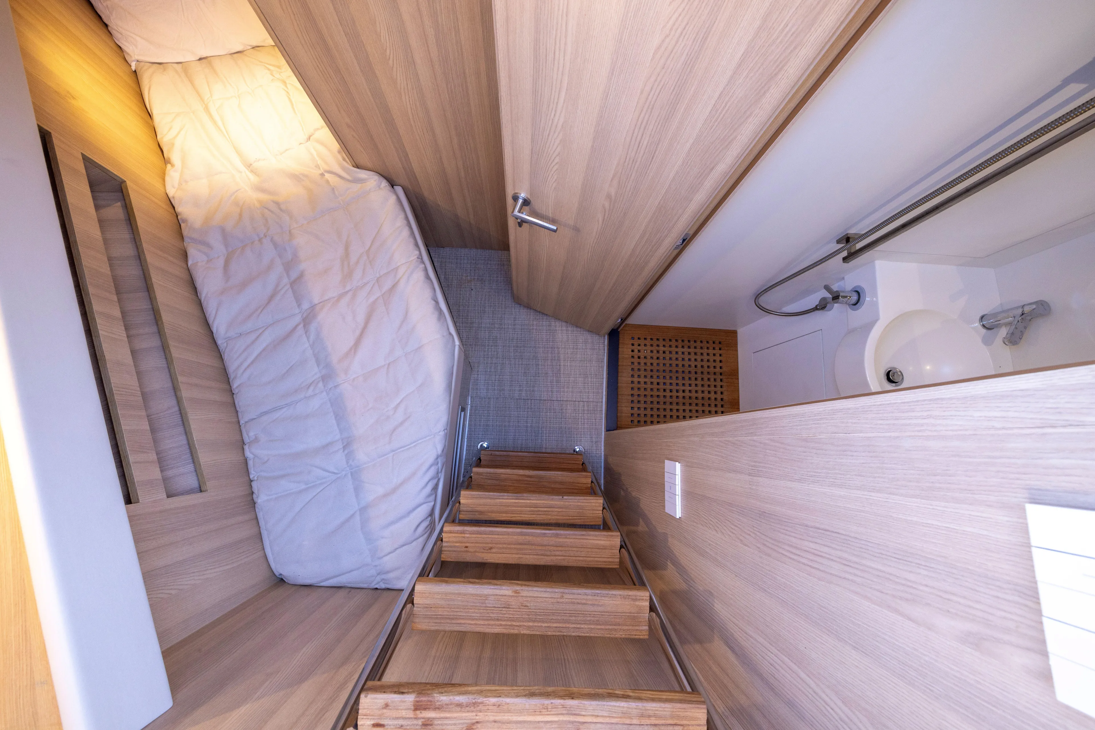 The Calm Down Yacht Photos Pics 2024 Bluegame BGX63 yacht interior with wooden stairs, cozy bed, and compact bathroom.