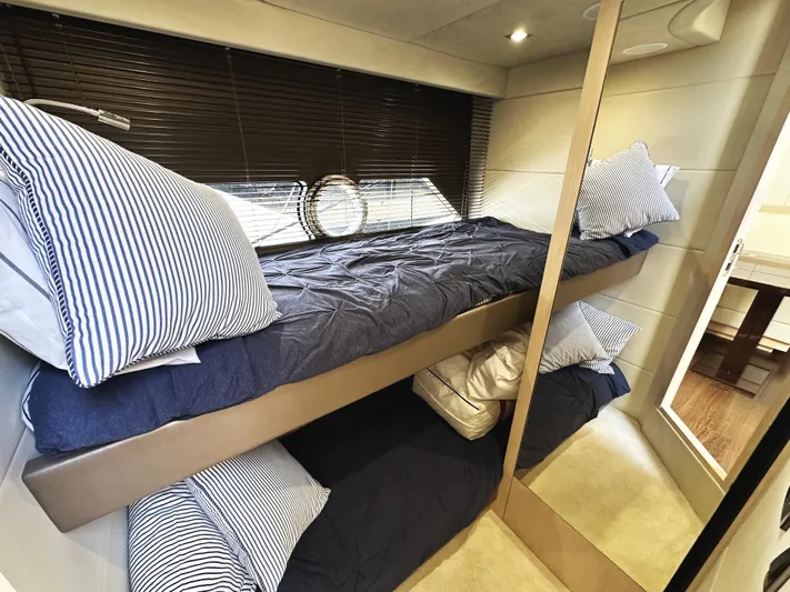 Tucker II Yacht Photos Pics Bunk beds in 2015 Sunseeker Predator 57 yacht cabin with striped bedding and porthole window.