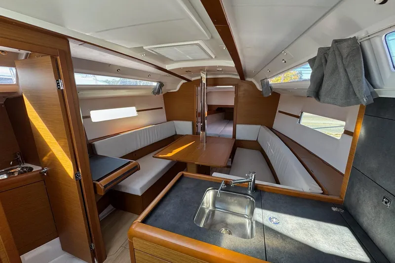  Yacht Photos Pics Interior of 2020 Jeanneau Sun Odyssey 349 sailboat with modern wood finish and seating area.