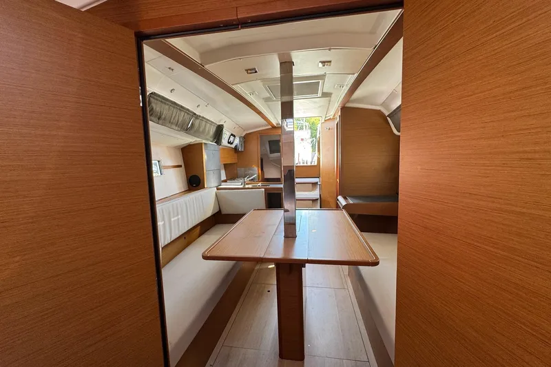  Yacht Photos Pics Interior of 2020 Jeanneau Sun Odyssey 349 sailboat, featuring wood finishes and seating area.