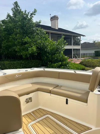 Outnumbered Yacht Photos Pics 2020 Scout 277LXF boat with tan seating, wooden deck, and house in the background.