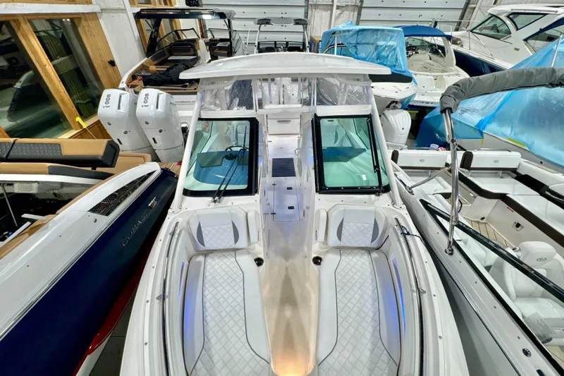  Yacht Photos Pics 2024 Pursuit DC 266 Dual Console boat in showroom, featuring sleek design and twin engines.