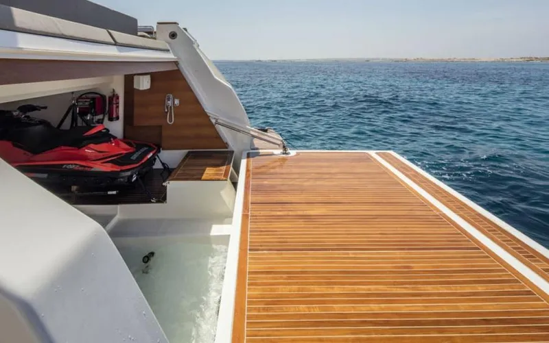  Yacht Photos Pics 2024 Custom Line Navetta 33 yacht with teak deck and jet ski, ocean backdrop.