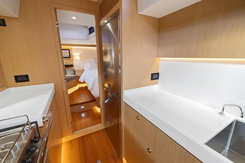 No Retreat Yacht Photos Pics Modern interior of 2020 Hylas H57 yacht, featuring sleek kitchen and cozy bedroom.