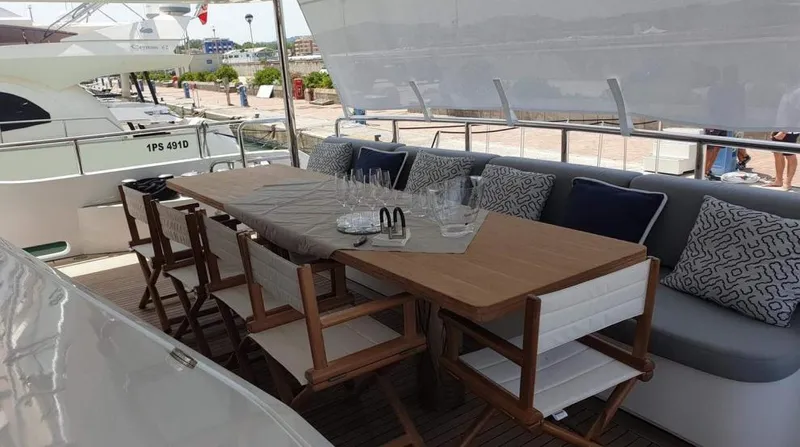  Yacht Photos Pics Outdoor dining area on a 2013 Benetti Delfino 93 yacht with wooden table and cushioned seating.