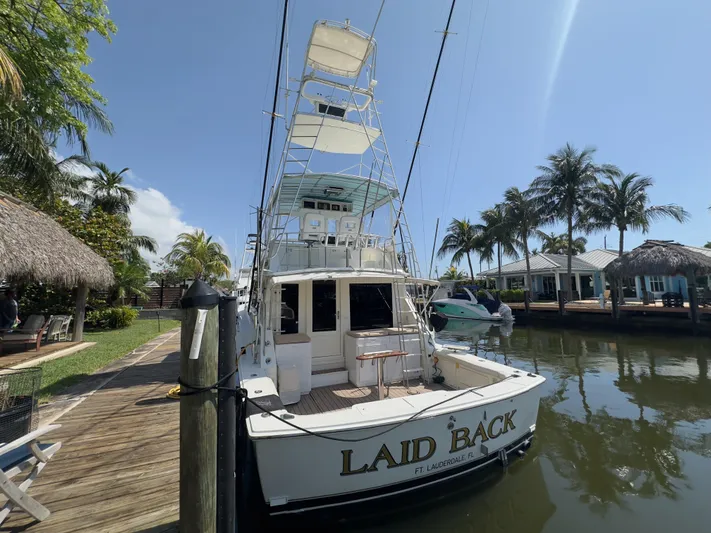 Laid Back Yacht Photos Pics 1983 Bertram 46 Convertible yacht docked, named "Laid Back," surrounded by palm trees.
