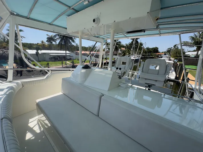 Laid Back Yacht Photos Pics 1983 Bertram 46 Convertible yacht interior with seating and helm, under a blue canopy.