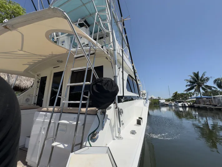 Laid Back Yacht Photos Pics 1983 Bertram 46 Convertible yacht docked by a calm waterfront under clear blue skies.
