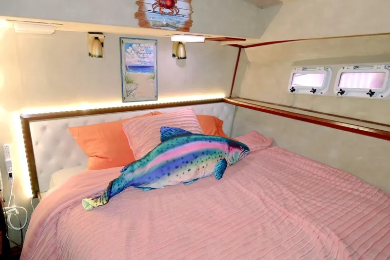 Laid Back Yacht Photos Pics Cozy bedroom in 1983 Bertram 46 Convertible with plush fish pillow and pink bedding.
