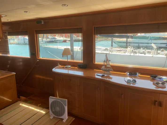  Yacht Photos Pics Luxurious yacht interior with wooden cabinetry, large windows, and marina view. ABD 60, 2006 model.