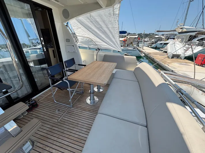  Yacht Photos Pics Flybridge seating area on 2020 Jeanneau Prestige 420, featuring a wooden table and marina view.