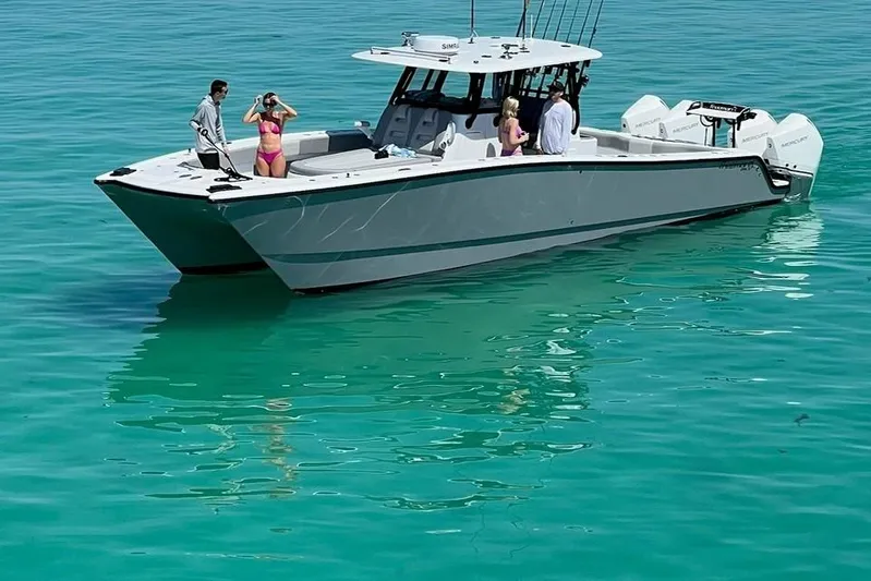 Arrogant 1 Yacht Photos Pics 2022 Freeman 37 Center Console boat on turquoise water with people onboard.