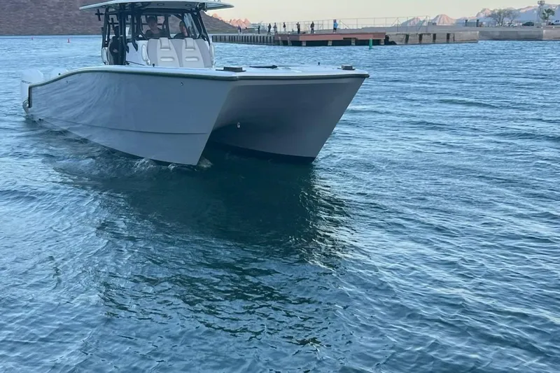 Arrogant 1 Yacht Photos Pics 2022 Freeman 37 Center Console boat cruising on calm water near a dock.