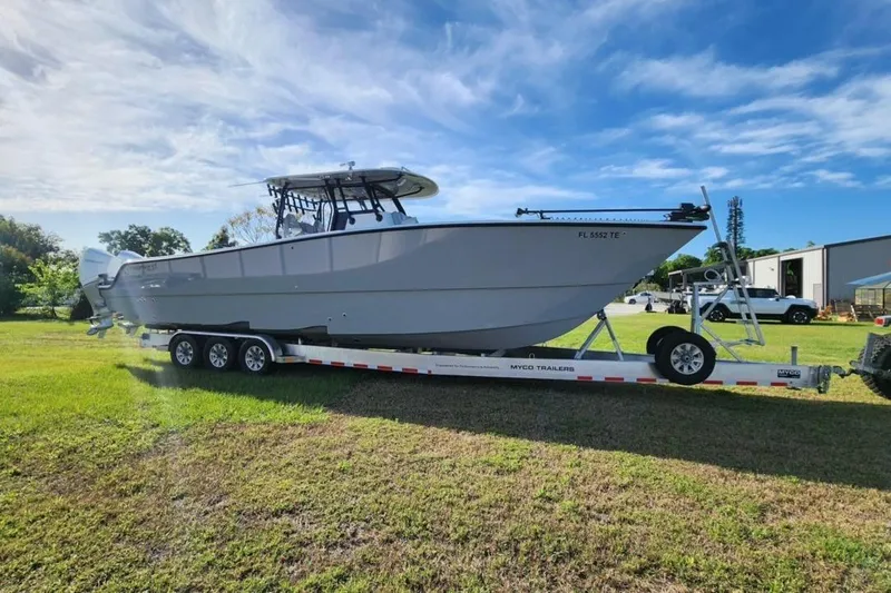 Arrogant 1 Yacht Photos Pics 2022 Freeman 37 Center Console boat on trailer, parked on grass under blue sky.