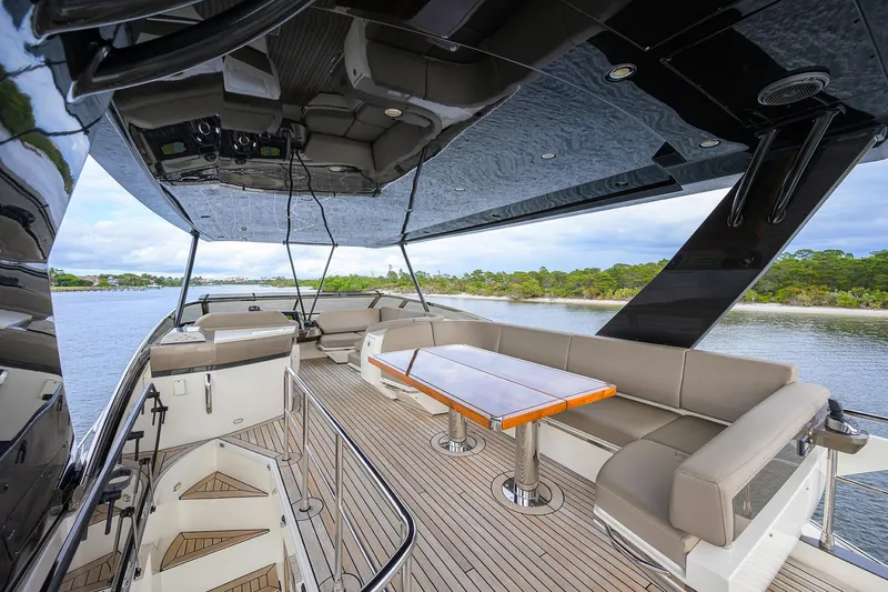 Andiamo Yacht Photos Pics Luxurious 2016 Marquis 660 Sport Yacht deck with seating and table, overlooking serene waters.