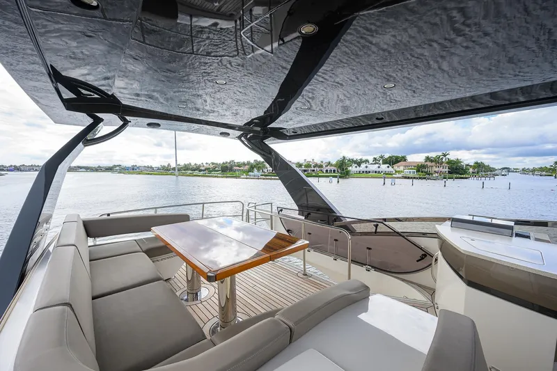 Andiamo Yacht Photos Pics Luxurious 2016 Marquis 660 Sport Yacht deck with seating and table, overlooking serene waterfront.