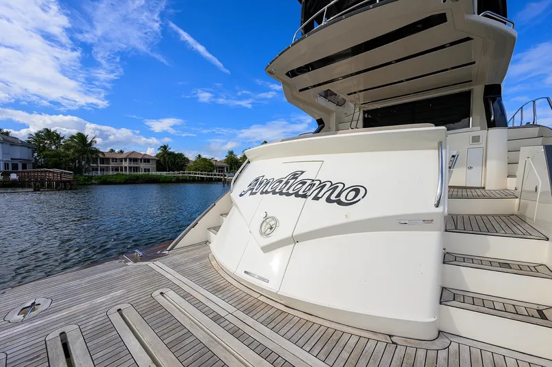 Andiamo Yacht Photos Pics 2016 Marquis 660 Sport Yacht docked by waterfront homes under blue sky.