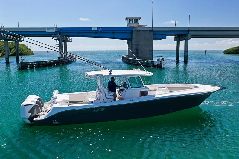  Yacht Photos Pics 2019 HCB 39 Speciale boat cruising under a bridge on clear blue water.
