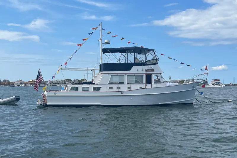 Revere Yacht Photos Pics 2002 Grand Banks 42 Classic yacht adorned with flags, anchored in a scenic harbor.
