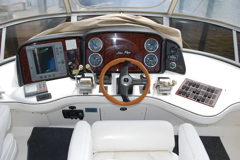  Yacht Photos Pics 2004 Sea Ray Sedan Bridge helm with wood accents, steering wheel, and navigation instruments.