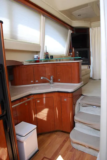  Yacht Photos Pics 2004 Sea Ray Sedan Bridge interior with wooden cabinetry, modern kitchen, and carpeted stairs.