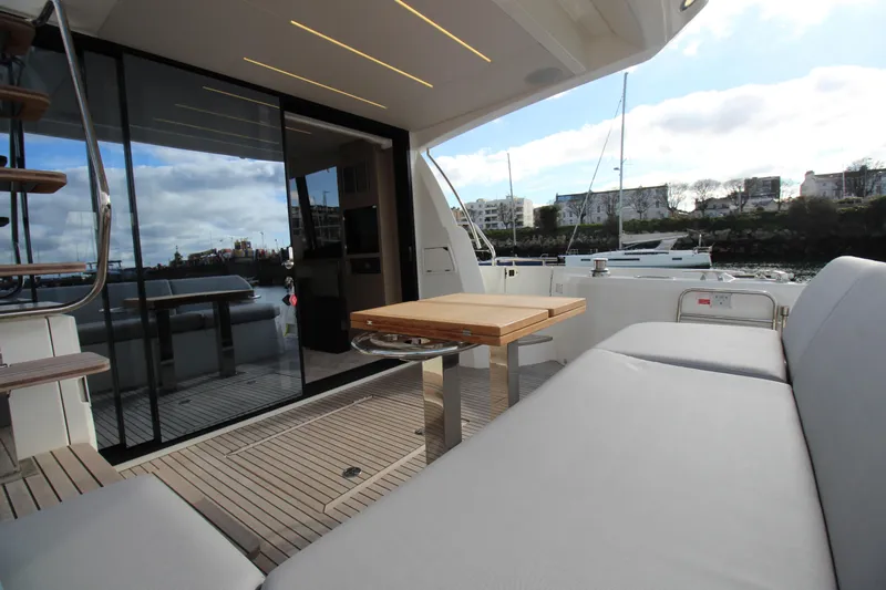  Yacht Photos Pics Luxurious 2025 Prestige 520 yacht deck with modern seating and table, docked at marina.