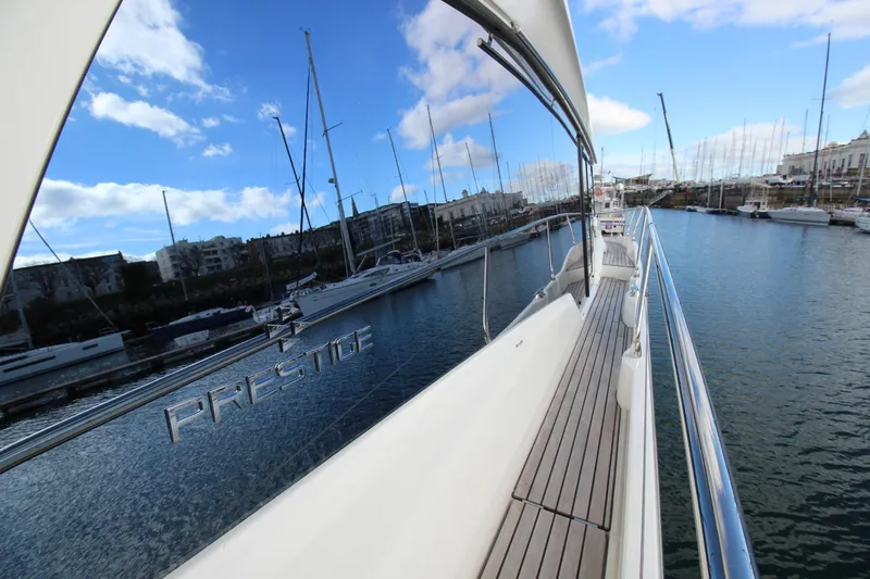  Yacht Photos Pics 2025 Prestige 520 yacht docked in a marina, reflecting clear blue sky and boats.