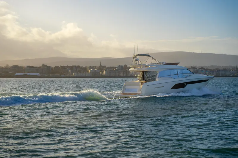  Yacht Photos Pics 2025 Prestige 520 yacht cruising on a scenic coastal waterway at sunset.