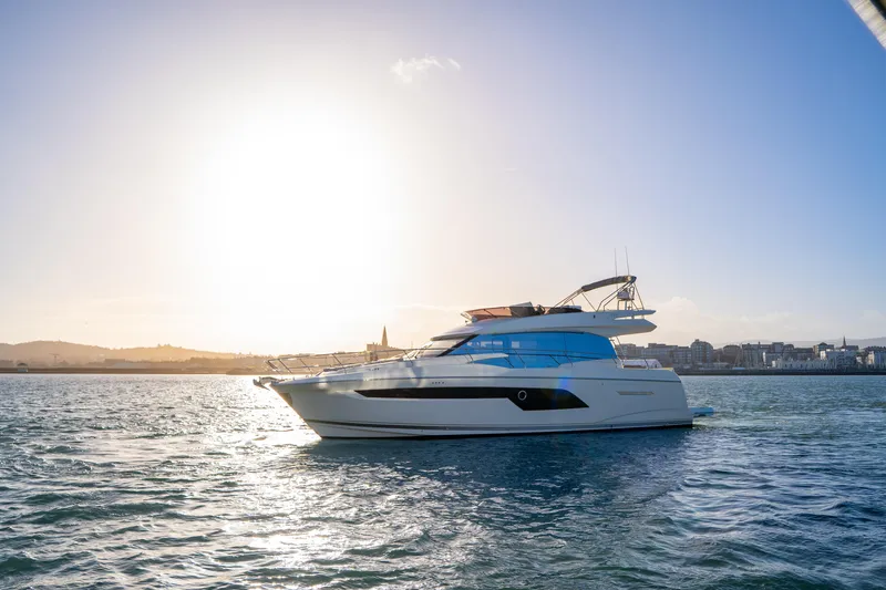  Yacht Photos Pics Luxury 2025 Prestige 520 yacht cruising on serene waters at sunset.