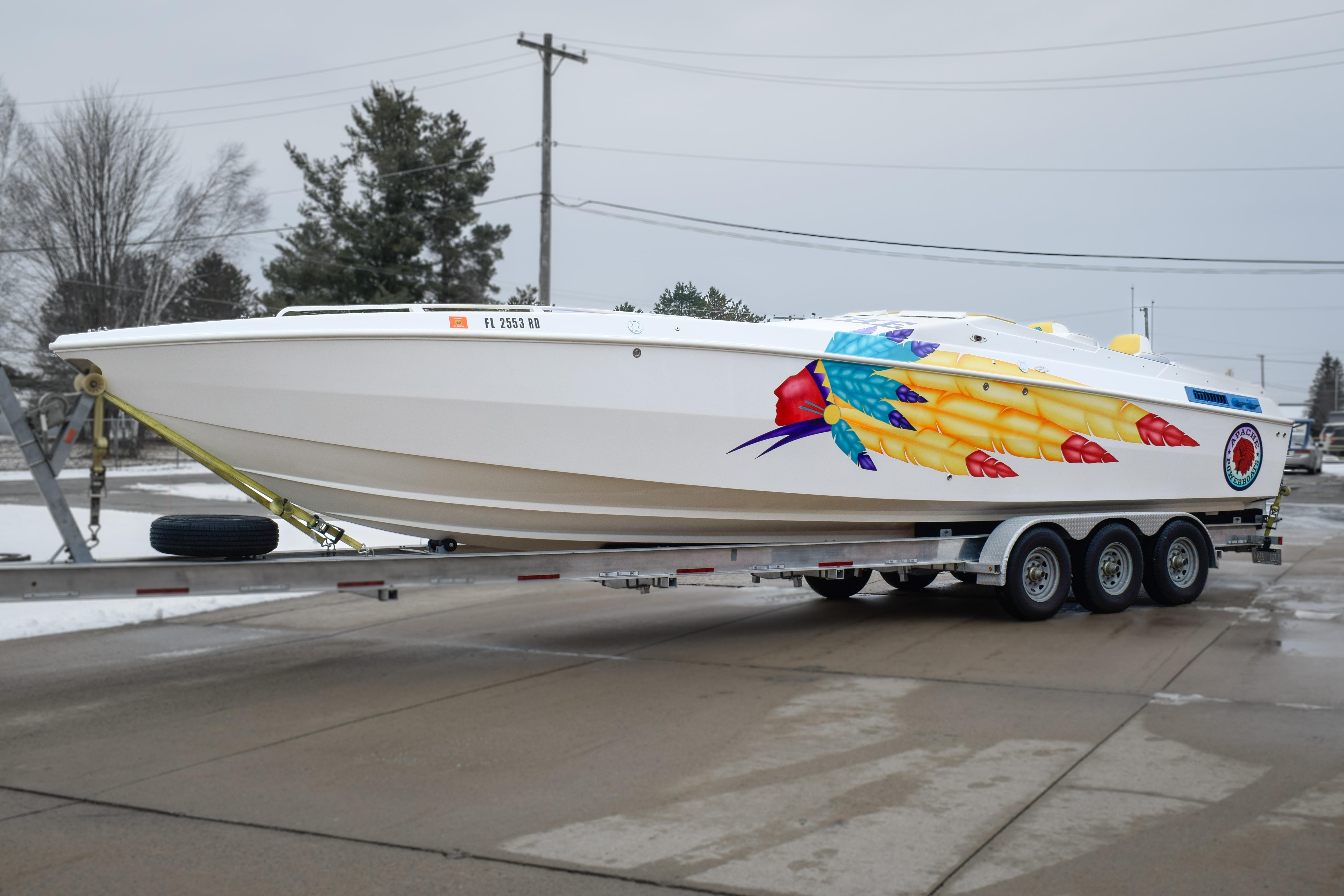 1998 Apache 36 WARRIOR boat with vibrant feather design on trailer.