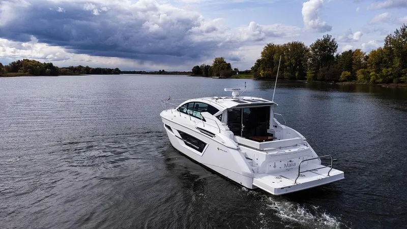  Yacht Photos Pics 2023 Cruisers Yachts 46 Cantius cruising on a serene lake under a cloudy sky.