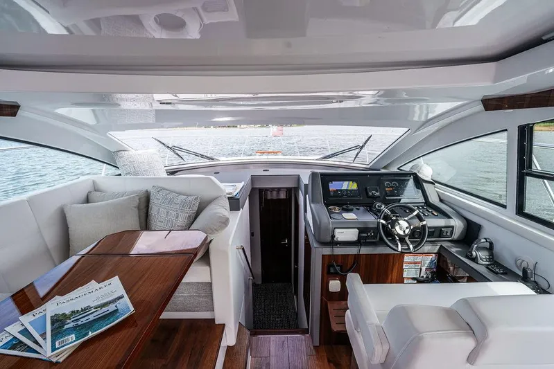  Yacht Photos Pics 2023 Cruisers Yachts 46 Cantius interior with helm, seating, and wooden table.