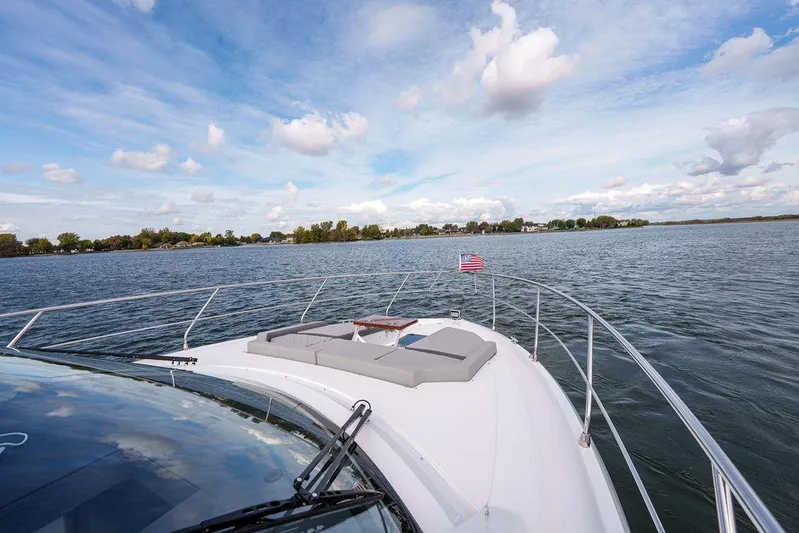  Yacht Photos Pics 2023 Cruisers Yachts 46 Cantius on serene water, featuring spacious deck and American flag.