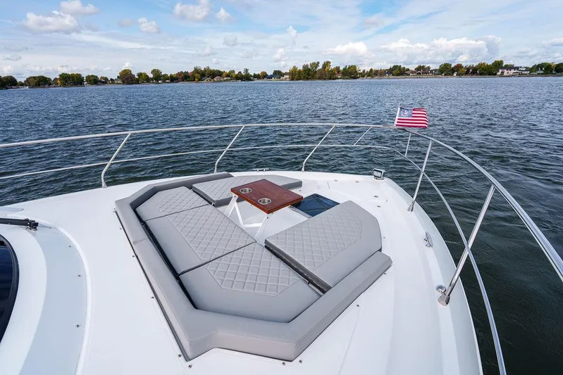  Yacht Photos Pics 2023 Cruisers Yachts 46 Cantius bow with seating, table, and American flag on a lake.