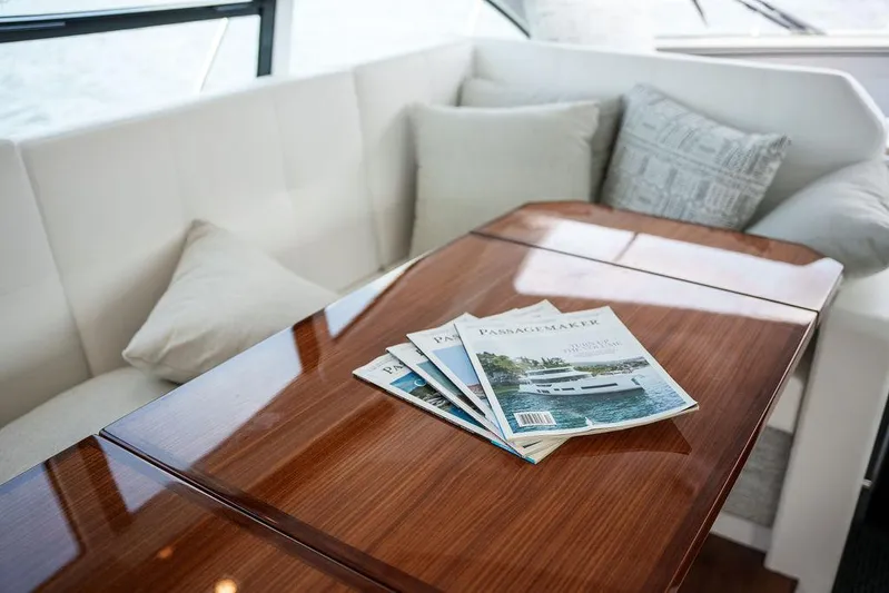  Yacht Photos Pics Luxurious interior of 2023 Cruisers Yachts 46 Cantius with magazines on wooden table.